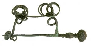 FIB-2561 - FibulebronzeFibule serpentiforme, dont l'ardillon en forme d'épingle passe par une tête perforée ; porte-ardillon filiforme prolongé par une spirale.