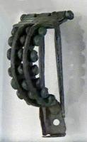 FIB-41736 - Fibule de type Bagendon à deux ardillons, type Lokošek 3bronzeFibule à charnière, arc double formant un arc de cercle, reliés par des axes transversaux portant des perles ; aux deux ardillons juxtaposés correspondent deux gouttières, placées de part et d'autre du pied simplement aplati.