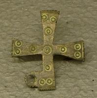 FIB-6014 - Fibule cruciformebronzeFibule en forme de croix latine, plate, à branches égales, légèrement évasées, ornée d'ocelles. Certains exemplaires disposent d'un anneau latéral pour une chaînette.