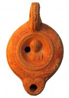 LMP-4339 - Lampe Loeschcke VIII : Buste fémininterre cuiteTPQ : 50 - TAQ : 150Lampe à bec rond; disque orné d'un buste féminin de face. Argile brique avec mica, engobe orange; base plate définie par un cercle incisé.