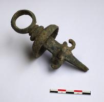 AJG-4045 - Anneau de joug
bronze
Anneau massif prolongé par une barre de section rectangulaire effilée à la pointe. L'anneau est séparé de la barre par deux disques de tailles différentes, perpendiculaires à l'axe de la barre, et une demi-sphère (diam. = 50 mm) elle aussi perpendiculaire à la barre. La partie inférieure de la barre présente de chaque côté deux appendices en forme d'anneaux ouverts. Entre ces deux petits anneaux, une courte barre de forme triangulaire, traverse la barre principale de part en part. D'un côté de la barre principale, cet appendice est aplati et strié par deux incisions parallèles horizontales.