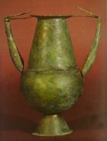 AMF-2001 - Amphore
bronze
Amphore martelée, panse globulaire surmontée d'un col tronconique et posée sur un pied évasé; deux anses tubulaires, également en tôle, attachées au sommet de la panse et sur la lèvre.