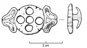 APT-4007 - Applique à tenons en T, type B1a
bronze
Applique pourvue au revers de 2 tenons en T, normalement guillochés sur la partie extérieure de la barrette ; l'objet est percé transversalement et un anneau retenu par un crampon replié à l'arrière y joue librement. Ce type a la forme d'un disque percé de 5 orifices et accosté de deux paires de pétales adossés.