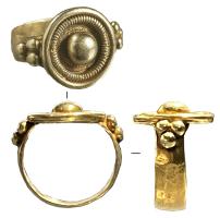 BAG-3045 - Bague
or
Bague à jonc rubané complété par un disque, accosté de groupes de globules, sur lequel se détachent des moulures concentriques et divers motifs.