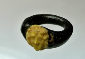 BAG-4078 - Bague à chaton moulé
verre
TPQ : 200 - TAQ : 400
Bague en verre, jonc plat de teinte sombre, avec un chaton rapporté en verre moulé blanc ou jaune clair figurant une tête de face (Satyre ?).