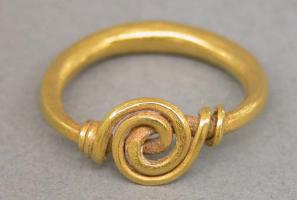 BAG-6009 - Bague à spiraleorTPQ : 750 - TAQ : 1000Bague formée d'un fil renflé sur le jonc, épaissi aux extrémités avec une section carrée, pour former un chaton en forme de spirale avec deux exytrémités nouées de part et d'autre du chaton.