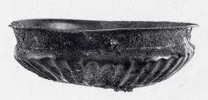 CPE-2002 - Coupe de type Colmar
bronze
Coupe en tôle martelée, à panse tronconique marquée de fines côtes en relief, forte carène, col vertical et lèvre légèrement déversée. Le fond est marqué de cercles concentriques et d'un petit ombilic.