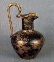 CRU-2003 - Cruche
bronze
Cruche à bec tréflé, col cylindrique, anse surélevée terminée à la base par une rosette ; panse ovoïde.