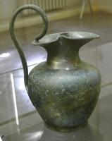 CRU-3029 - Cruche à bec tréflé
bronze
Cruche à panse ovoïde, épaule marqué et col étroit, largement ouvert au sommet pour former un bec tréflé ; anse surélevée, à jonc mince, venant se fixer à l'intérieur du bec et sur la panse.