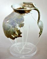 CRU-4073 - Cruche de type Tassinari C.1221
bronze
Cruche à panse ovoïde, bord trapu avec une lèvre oblique, déversée vers l'extérieur. L'anse rapportée sur la panse et la lèvre, incisée en chevrons sur la partie externe, repose sur une attache inférieure foliacée, avec au sommet deux bras en forme de têtes d'oiseaux enserrant la lèvre, de part et d'autre d'un long poucier en forme de doigt, s'avançant au-dessus de l'ouverture.