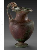 CRU-4120 - Cruche
bronze
Cruche à panse de profil semi-ovoïde, surmontée d'un col étranglé à large ouverture tréflée ; l'anse, massive et légèrement remontante, s'appuie sur l'épaule et vient se fixer sur la lèvre, avec un lion dont les pattes antérieures encadrent le bec; piédouche étroit.