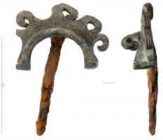 CVC-3001 - Clavette de char
bronze, fer
Clavette en bronze, coulée sur une forte tige en fer, de section quadrangulaire;  la tête en demi-cercle comporte sur le bord externe 5 volutes tournées vers l'extérieur; l'étrier renforcé par un angle repose sur deux butées; un anneau latéral permet d'assurer la clavette sur l'extrémité de l'essieu.