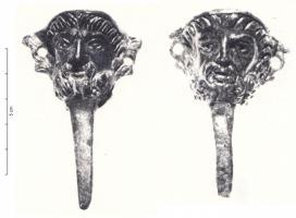 CVC-4013 - Clavette de char à décor moulé
bronze
Clavette dont le sommet figure une tête virile, barbue, au regard sévère (Jupiter ?) ; un anneau de chaque côté.