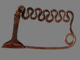 FIB-2618 - Fibule serpentiforme corse
bronze
Fibule à ressort unilatéral, large spire ; l'arc est constitué d'un segment rectiligne et serpentant, constitué d'une dizaine d'ondulations, sans boucle. Le pied, en tige rectiligne en angle droit avec l'arc, se termine par un porte-ardillon en étrier, en tôle.