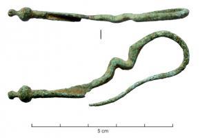 FIB-2647 - Fibule à disque d'arrêtbronzeTPQ : -500 - TAQ : -400Fibule à arc généralement serpentiforme, à 2 ou 3 méandres, sans boucles, dont l'arc se prolonge directement par l'ardillon, sans ressort, mais avec un disque d'arrêt entre les deux. Le pied allongé, formant un porte-ardillon étiré en gouttière, est terminé par un bouton (simple ou vasiforme) placé dans l'axe du porte-ardillon.