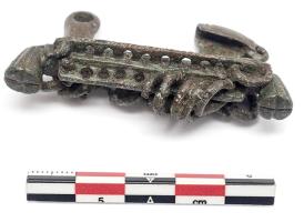 FIB-31023 - Fibule à décor d'anneaux
bronze
TPQ : -475 - TAQ : -250
Fibule coulée, à double pied disposés symétriquement aux extrémités d'un arc formant une barre rectiligne perforée et ornée d'anneaux ; pieds massifs redressés, en forme de fleurs.