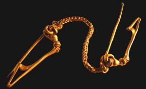 FIB-3821 - Fibule à ailettes naissantes
or
TPQ : -70 - TAQ : -30
Fibule à ailettes naissantes, à tête élargie recouvrant un ressort à quatre spires et corde externe ; le sommet de l'arc est coudé et occupé par plusieurs moulures, bagues et ailettes peu développée ; le porte-ardillon triangulaire est ajouré ou fenestré.