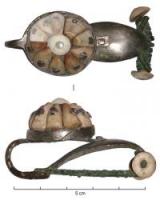 FIB-3904 - Fibule laténienne de type Münsingen
argent
TPQ : -300 - TAQ : -250
Fibule à arc plat, foliacé, avec un ou plusieurs ornements rivetés en corail ; ressort à 6 ou 8 spires, corde interne ou externe ; le pied replié en direction de l'arc se termine par un disque et un bouton ; le disque présente une collerette cylindrique, ornée d'incisions en ligne brisée, et un disque perforé pour la fixation d'un décor en bâtonnets de corail rivetés.