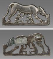 FIB-41771 - Fibule zoomorphe groupe : Louve et Jumeaux
argent
TPQ : 1 - TAQ : 250
Dans un cadre en demi-cercle, une louve debout vers la droite allaite deux jumeaux se faisant face; au-dessus, feuilles de lierre; au revers, articulation à ressort sur axe, monté sur une plaquette coulée.