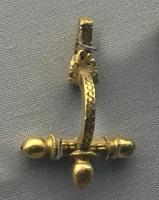 FIB-41802 - Fibule cruciforme Keller/Pröttel 1
or
TPQ : 275 - TAQ : 340
Fibule cruciforme précoce, à pied court, arc étroit et bras réduits, peu ou pas décorés et terminés par de tout petits bulbes; le bouton central fait corps avec l'arc.