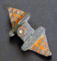 FIB-4198 - Fibule symétrique émaillée
bronze
TPQ : 75 - TAQ : 125
Fibule symétrique, à décor émaillé. Le corps central de forme carrée et ornée d'un bouton, le plus souvent, conique lui-même émaillé Ce motif sépare deux parties symétriques de forme triangulaire, ornées d'un semis de triangles émaillés.