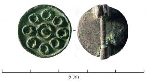 FIB-4202 - Fibule circulaire émailléebronzeTPQ : 150 - TAQ : 300Fibule circulaire creusée pour un décor d'émaux champlevés : autour d'un disque central marqué d'un point, huit disques régulièrement répartis.