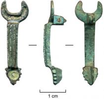 FIB-4216 - Fibule émailléebronzeTPQ : 150 - TAQ : 300Arc étroit et cannelé, rectiligne et légèrement surélevé par rapport aux extrémités, occupées par un disque émaillé au-dessus du porte-ardillon, et un croissant émaillé au-dessus de la charnière.