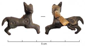 FIB-4688 - Fibule zoomorphe : chien
bronze
TPQ : 100 - TAQ : 400
Broche plate en forme de chien courant à droite, la tête en ronde-bosse tournée vers le spectateur; deux cercles oculés (pour émail ?) sur le corps; articulation par ressort monté sur axe et une seule plaquette.