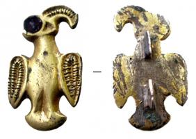 FIB-5092 - Fibule aviformeargent doréTPQ : 400 - TAQ : 500Fibule en forme d'aigle, la tête à droite, l'œil incrusté d'un grenat, le bec et les ailes rehaussés d'un filet grèneté, centré.