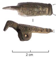 FIB-6071 - Fibule zoomorphe : oiseauargentTPQ : 700 - TAQ : 1000Fibule en forme d'oiseau aux ailes repliées, figuration schématique avec le corps couvert de cercles oculés; corps creux; système d'articulation à deux plaquettes perforées émergeant à la place des pattes, porte-ardillon sous la queue.