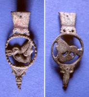 FRT-8001 - Ferret à médaillon figurébronzeTPQ : 1400 - TAQ : 1550Ferret en trois parties : l'attache supérieure rivetée sur l'extrémité de la ceinture, avec un décor gravé; une partie médiane en forme de médaillon ajouré, orné d'un relief figuré : Hercule étouffant le lion de Némée, en général avec une ou deux lettres gothiques; un lest en forme de tête animale.