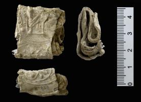 IND-7008 - Médaillon figuréplombTPQ : 1200 - TAQ : 1400médaillon moulé comportant une figure assise en majesté, vêtue d'un long manteau plissé, portant un sceptre dans la main droite ; autour, rinceaux.