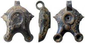 LMP-3041 - Lampe moulée à double bec
terre cuite
TPQ : -125 - TAQ : -50
Lampe moulée, anse en anneau simple rapportée. Réservoir à profil biconvexe. Le large bandeau porte un décor végétal. Corymbe entre les becs. Petit disque en simple cuvette limité par un anneau plat. Deux ailerons latéraux en forme de feuille. Double becs cylindriques au bout en large anneau plat. Base en fer à cheval fermé dont les branches se poursuivent sous les becs pour assurer l'équilibre. Restes de vernis noir brillant.