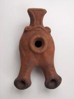 LMP-3130 - Lampe orientale 2 becs Alpha
terre cuite
TPQ : -120 - TAQ : -50
Lampe à réservoir rond. Deux longs becs tubulaires avec terminaison quasi-enclume, séparés du centre de la lampe par une incision en zigzag. Anse striée avec petit réflecteur en forme de T né d'une volute en relief soulignée par un trait horizontal en relief. Argile orange, engobe orange. Base plate définie par un cercle incisé.