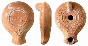 LMP-4099 - Lampe syro-palestinienne A o C
terre cuite
TPQ : 100 - TAQ : 300
Lampe moulée à anse verticale non percée. Bec en bras d'ancre flanqué de deux volutes simples dont un rappel incisé marque le dessous. Trois palmes à son départ. Petit disque sans décor. Couronne de laurier sur le bandeau. Base en bourrelet avec une marque d'atelier incisée avant cuisson : A o C.