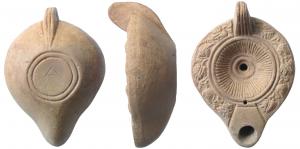 LMP-4104 - Lampe corinthienne, pampres
terre cuite
TPQ : 250 - TAQ : 300
Lampe moulée, anse non percée à trois sillons. Bec arrondi limité par un trapèze. Le bandeau est orné d'une couronne de pampres de vigne. Deux bourrelets entourenr le disque au décor de stries rayonnantes. Un bourrelet entoure le trou d'alimentation. Base circulaire plate limitée par deux sillons concentriques,  un alpha incisé.