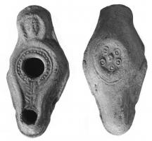 LMP-41482 - Lampe syrienne tardive 
terre cuite
TPQ : 400 - TAQ : 600
Lampe allongée à long bec, canal décoré d'une feuille de palme et anse plastique rectangulaire décorée d'une tête humaine; le rséervoir à large trou de remplissage centré est orné de motifs géométriques, poinllés ou signes alternés.