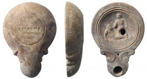 LMP-41533 - Lampe à volutes doubles : L M ADIEC Lutteurs
terre cuite
TPQ : 90 - TAQ : 140
Lampe moulée, sans anse. Réservoir circulaire de profil convexe. Bandeau étroit penché vers l'extérieur. Disque en cuvette limitée par deux cercles en creux. Décor : deux lutteurs de pancrace, l'un debout à droite, l'autre au sol. Bec long arrondi, flanqué de deux volutes doubles se poursuivant sous le bec. Base plate limitée par un cercle en creux, estampée L.M ADIEC.