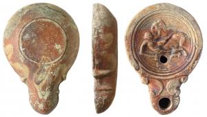 LMP-41534 - Lampe Loeschcke IV : Amazone
terre cuite
TPQ : 50 - TAQ : 150
Lampe moulée sans anse. Réservoir circulaire de profil convexe. Bandeau plat et étroit.  Disque circulaire limité par trois sillons concentriques. Décor : amazone tombant de son cheval. Elle tient une hache dans sa main droite et un pelta en forme d'aigle dans l'autre. Bec long arrondi, à volutes doubles se poursuivant sous le bec. Base circulaire plate limitée par un sillon.  Restes d'engobe rouge brique.