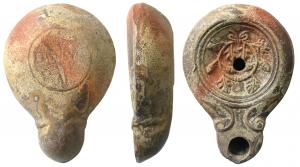 LMP-41542 - Lampe Loesckcke V : L MVN SVC
terre cuite
TPQ : 75 - TAQ : 120
Lampe moulée, sans anse. Réservoir piriforme de profil biconvexe asymétrique. Bandeau penché vers l'extérieur. Disque circulaire limité par deux sillons. Décor : couronne de feuilles de lierre et de glands. Bec long arrondi , à volutes simples se poursuivant sous le bec. Base circulaire limitée par un sillon, estampillée L.MVN SVC. Restes d'engobe de couleur variée sur toute la lampe.