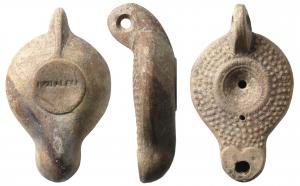 LMP-41552 - Lampe à décor de globules : IVNI ALEXI
terre cuite
TPQ : 120 - TAQ : 200
Lampe moulée, anse verticale à deux sillons sur la tranche. Réservoir circulaire de profil biconvexe. Large bandeau  orné de quatre rangées de globules  se poursuivant vers ou sur le bec : bec et réservoir peuvent être séparés ou reliés par un cnal. Petit disque limité par un sillon et un bourrelet en forme de palme. Trou d'évent. Bec long cordiforme.Base plate circulaire en léger relief, estampillée IVNI ALEXI en creux. Engobe brun-rouge à marron violacé.