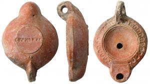 LMP-41567 - Lampe à bec rond limité par un trait : C IVN DRAC
terre cuite
TPQ : 120 - TAQ : 200
Lampe moulée, anse verticale percée à deux sillons sur la tranche. Réservoir circulaire à profil biconvexe. Bandeau penché vers l'extérieur, décoré d'oves doubles. Disque en cuvette limitée par deux sillons concentriques.Bec arrondi limité par un trait droit. Base circulaire plate en léger relief limitée par un sillon. Estampée C IVN DRAC  en creux, lisible bec en haut. Deux globules au départ de l'anse. Engobe rouge brique sur toute la lampe.