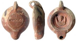 LMP-41569 - Lampe à bec rond limité par un trait : Luna,  I / M NOV IVSTI
terre cuite
TPQ : 120 - TAQ : 180
Lampe moulée, anse verticale percée à deux sillons sur la tranche. Réservoir circulaire à profil biconvexe. Bandeau penché vers l'extérieur, disque en cuvette limitée par deux sillons concentriques. Décor : Luna sur un croissant de lune. Bec arrondi limité par un trait droit ponctué aux extrémités. Base circulaire plate en léger relief limitée par un sillon estampillée I / M NOV IVST surmonté par un I. Engobe marron rouge sur toute la lampe.