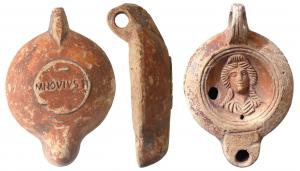 LMP-41571 - Lampe à bec rond limité par un trait : Buste, M NOV IVSTI
terre cuite
TPQ : 120 - TAQ : 180
Lampe moulée, anse verticale percée à deux sillons sur la tranche. Réservoir circulaire à profil biconvexe asymétrique. Bandeau penché vers l'extérieur, disque en cuvette limitée par deux sillons concentriques. Décor : buste féminin. Bec arrondi limité par un trait droit ponctué aux extrémités. Base circulaire plate en léger relief limitée par un sillon estampillée M NOV IVS TI . Engobe  rouge brique sur toute la lampe.