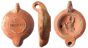 LMP-41572 - Lampe à bec rond limité par un trait : Fortune IVNI ALEXI
terre cuite
TPQ : 120 - TAQ : 200
Lampe moulée, anse verticale percée à deux sillons sur la tranche. Réservoir circulaire à profil biconvexe. Bandeau penché vers l'extérieur, disque en cuvette limitée par deux sillons concentriques. Décor : Fortune à gauche tenant un gouvernail et une corne d'abondance. Bec arrondi limité par un trait droit ponctué aux extrémités. Base circulaire plate en léger relief limitée par un sillon, estampillée en creux IVNI ALEXI. Engobe rouge orangé sur toute la lampe.