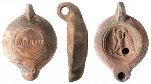 LMP-41574 - Lampe à bec rond limité par un trait : IVNI ALEXI  Amour
terre cuite
TPQ : 120 - TAQ : 200
Lampe moulée, anse verticale percée à deux sillons sur la tranche. Réservoir circulaire à profil biconvexe. Bandeau penché vers l'extérieur, disque en cuvette limitée par deux sillons concentriques. Décor : amour, à gauche, tenant un arc de la main gauche et la massue d'Hercule de la droite. Bec arrondi limité par un trait droit ponctué aux extrémités. Base circulaire plate en léger relief limitée par un sillon estampillée IVNI ALEXI. Engobe rouge marron  sur toute la lampe.