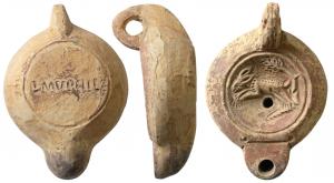 LMP-41575 - Lampe à bec rond limité par un trait : Lièvre, L MVPHIL
terre cuite
TPQ : 75 - TAQ : 130
Lampe moulée, anse verticale percée à deux sillons sur la tranche. Réservoir circulaire à profil biconvexe asymétrique. Bandeau penché vers l'extérieur, disque en cuvette limitée par un sillon. Décor : lièvre courant, à gauche, sous un arbre. Tridan en relief côté gauche sous le réservoir. Bec arrondi limité par un trait droit ponctué aux extrémités. Base circulaire plate en léger relief limitée par un sillon, estampillée L.MVPHIL. Restes d'engobe rouge marron  sur toute la lampe.