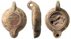 LMP-41579 - Lampe à bec rond limité par un trait : C IVN ALEX Oiseau
terre cuite
TPQ : 120 - TAQ : 200
Lampe moulée, anse verticale percée à deux sillons sur la tranche. Réservoir circulaire à profil biconvexe assymétrique. Bandeau penché vers l'extérieur, disque en cuvette limitée par un sillon . Décor : oiseau à droite, sur une branche. Bec arrondi limité par un trait droit ponctué aux extrémités. Base circulaire plate en léger relief limitée par un sillon estampillée C IVN ALEX en relief dans un cartouche en creux. Engobe marron vineux sur toute la lampe.