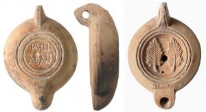 LMP-41580 - Lampe à bec rond limité par un trait : PVLL AENI Feuilles
terre cuite
TPQ : 100 - TAQ : 200
Lampe moulée, anse verticale percée à deux sillons sur la tranche. Réservoir circulaire à profil biconvexe. Bandeau penché vers l'extérieur, disque en cuvette limitée par deux sillons concentriques. Décor : deux palmes verticales symétriques. Bec arrondi limité par un trait droit. Quatre petits traits le relie au disque. Base circulaire plate  limitée par un anneau plat, gravée PVLL ANEI. Restes d'engobe rouge marron  sur toute la lampe.