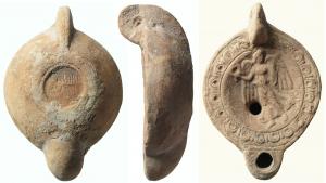 LMP-41590 - Lampe à bec rond limité par deux traits : Victoire, S ANNI ON
terre cuite
TPQ : 150 - TAQ : 250
Lampe moulée, anse verticale a moitié percée à deux sillons sur la tranche. Réservoir circulaire à profil convexe. Bandeau plat portant une couronne de godrons alternés avec des bâtonnets rayonnants. Disque en cuvette limitée par un sillon circulaire. Décor : Victoire de face. Elle tient une couronne enrubannée de la main droite et une palme  dans l'autre. Bec arrondi limité par deux traits gravés. Base circulaire plate en creux bordée par un fin bourrelet et deux sillons concentriques,  porte une signature gravée SANNI/ON  Restes d'engobe brique sur toute la lampe.